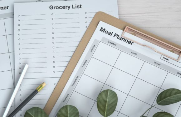 weekly meal planner template with separate meal planner and grocery list pages on clipboard and table